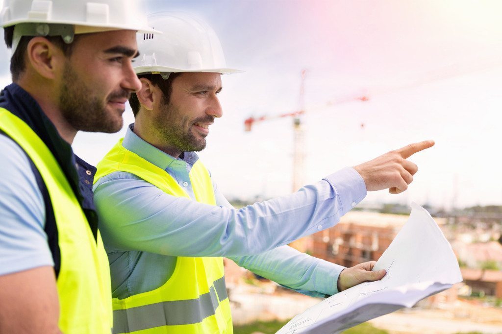 Worker and architect watching some details on a construction construction